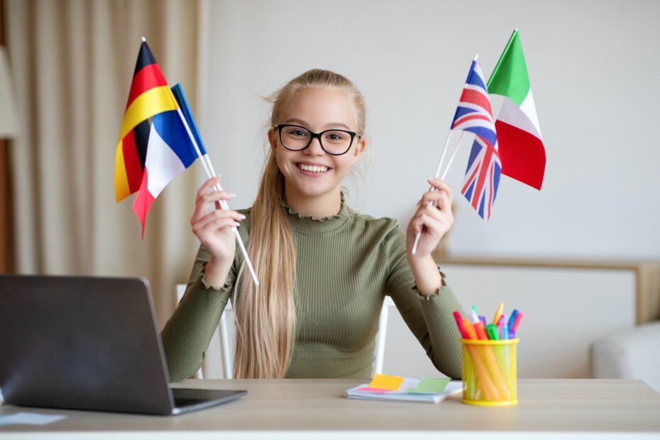 Cheerful teen girl sitting at home using laptop, studying languages