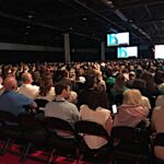 Large Audience crowd gathering at a conference watching the guest speaker on the main stage