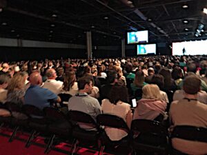 Large Audience crowd gathering at a conference watching the guest speaker on the main stage